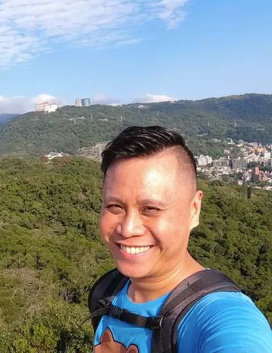 {Selfie portrait of wellness coach Zhi Lee above a forest, smiling at the camera.}